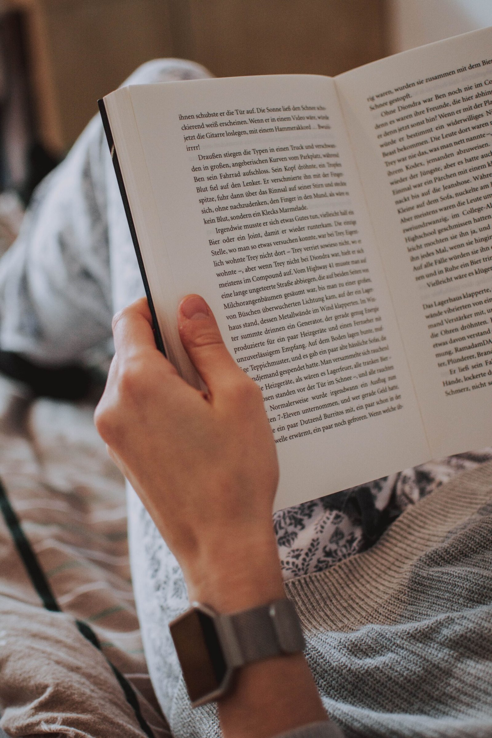 Person relaxing and reading a physical book instead of a screen, an example of a digital detox activity