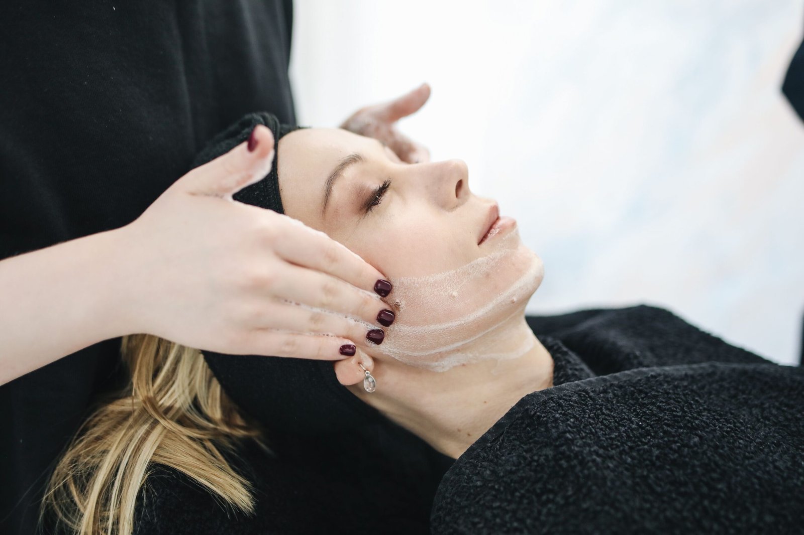 Side view of a woman receiving a facial massage, illustrating the muscle engagement used in face yoga