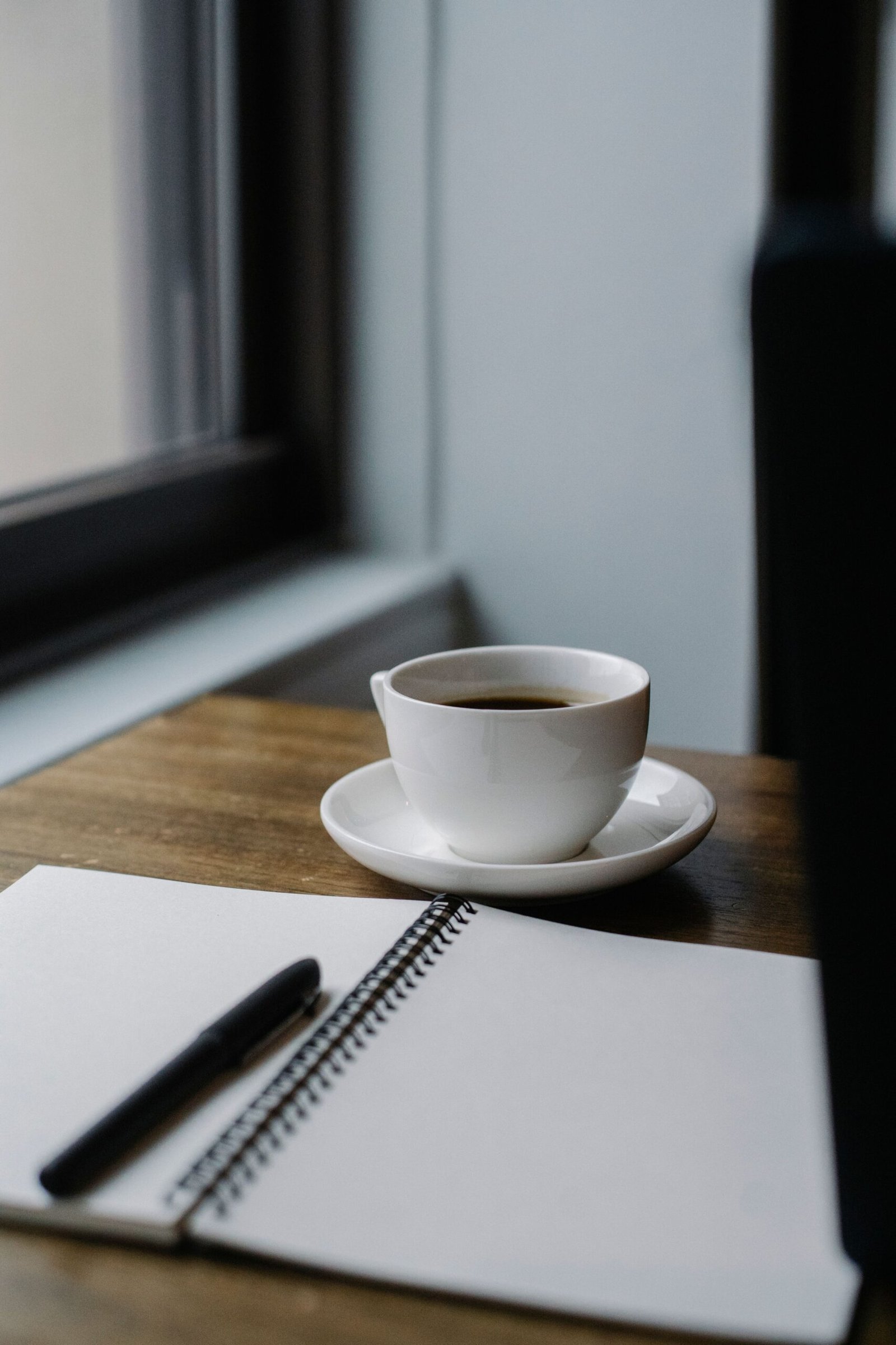 Cup of coffee with an open journal on a table for daily journaling practice