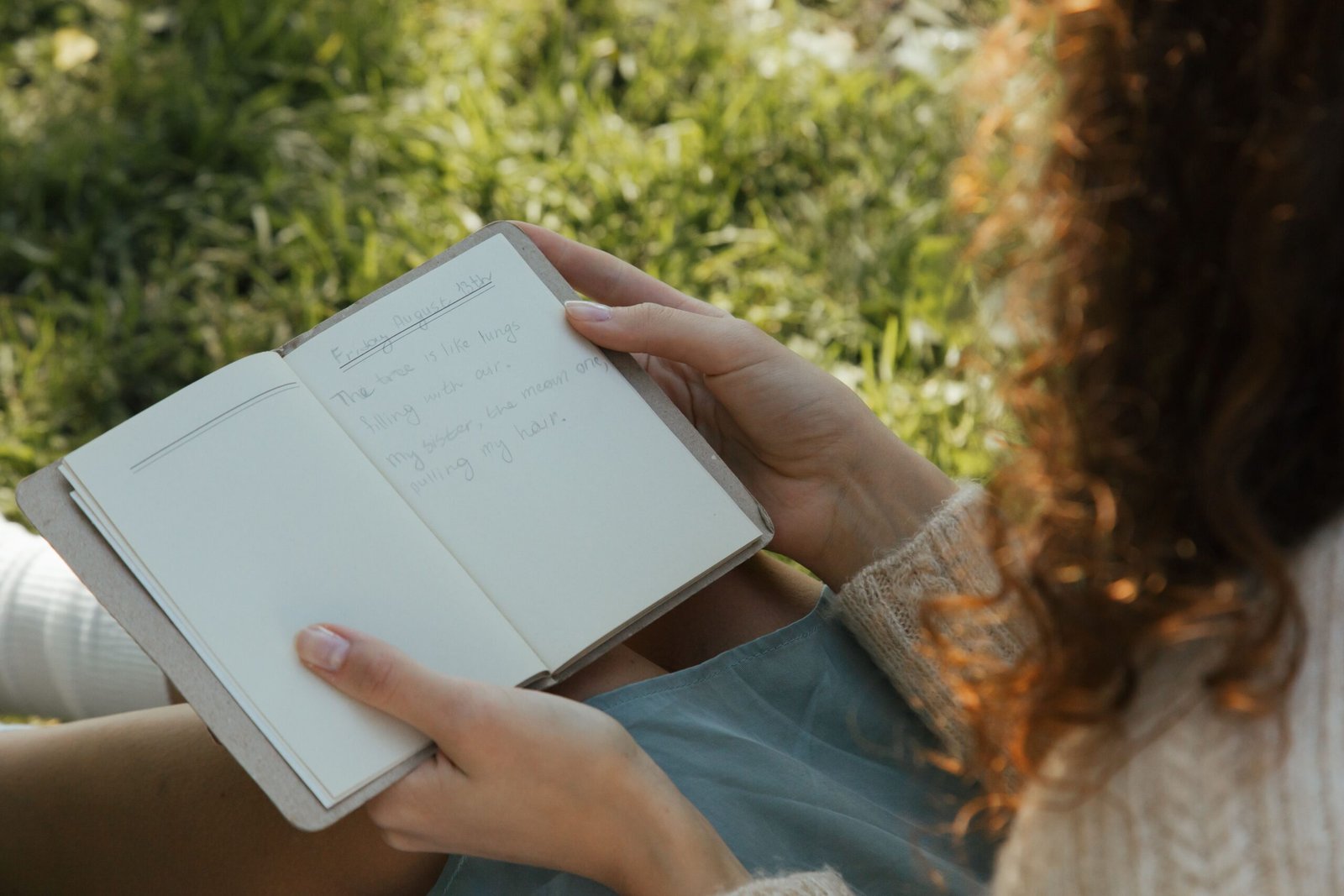 Woman writing in a diary in the park, reflecting on her thoughts to challenge negative self-talk
