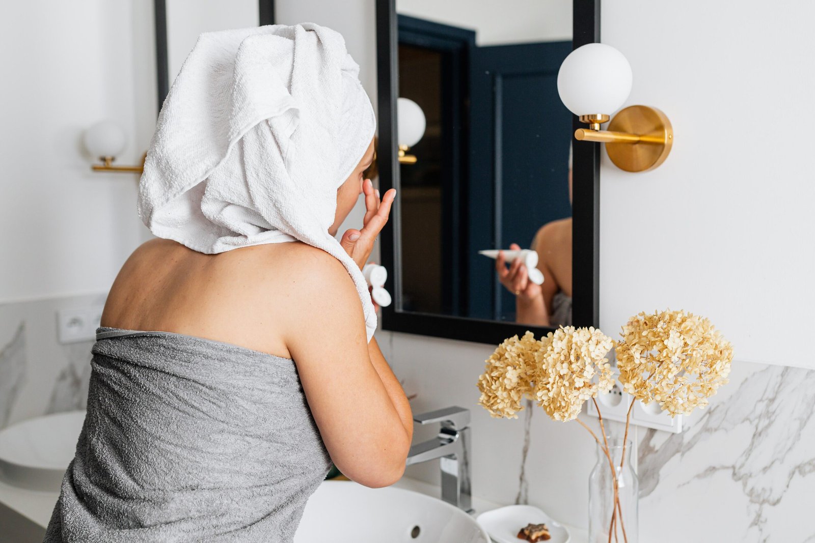 Woman applying skincare product to her face as part of a gentle routine for hormonal acne