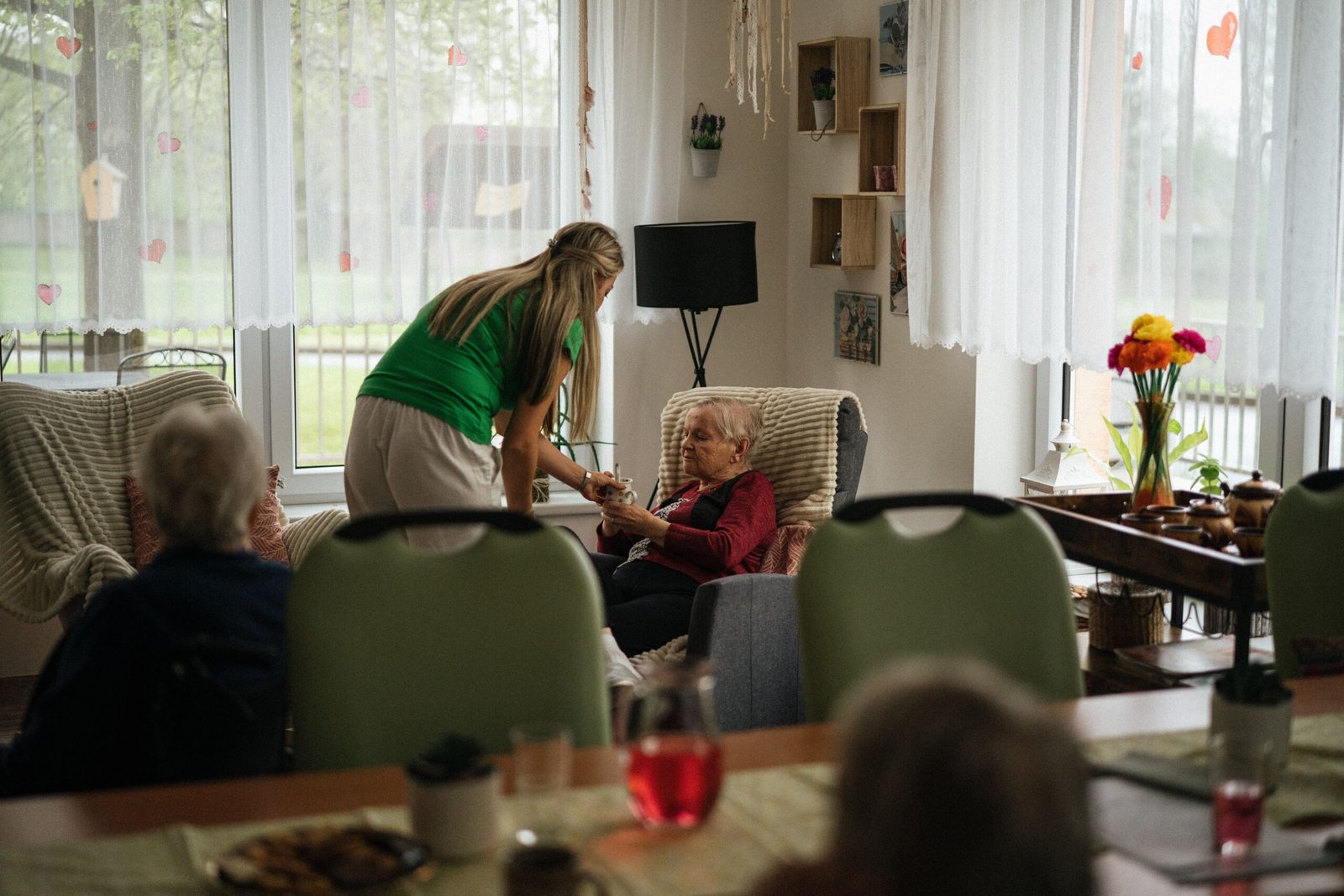 Caregiver assisting an elderly woman with tea in a cozy setting, representing the caregiving relationship at the heart of compassion fatigue