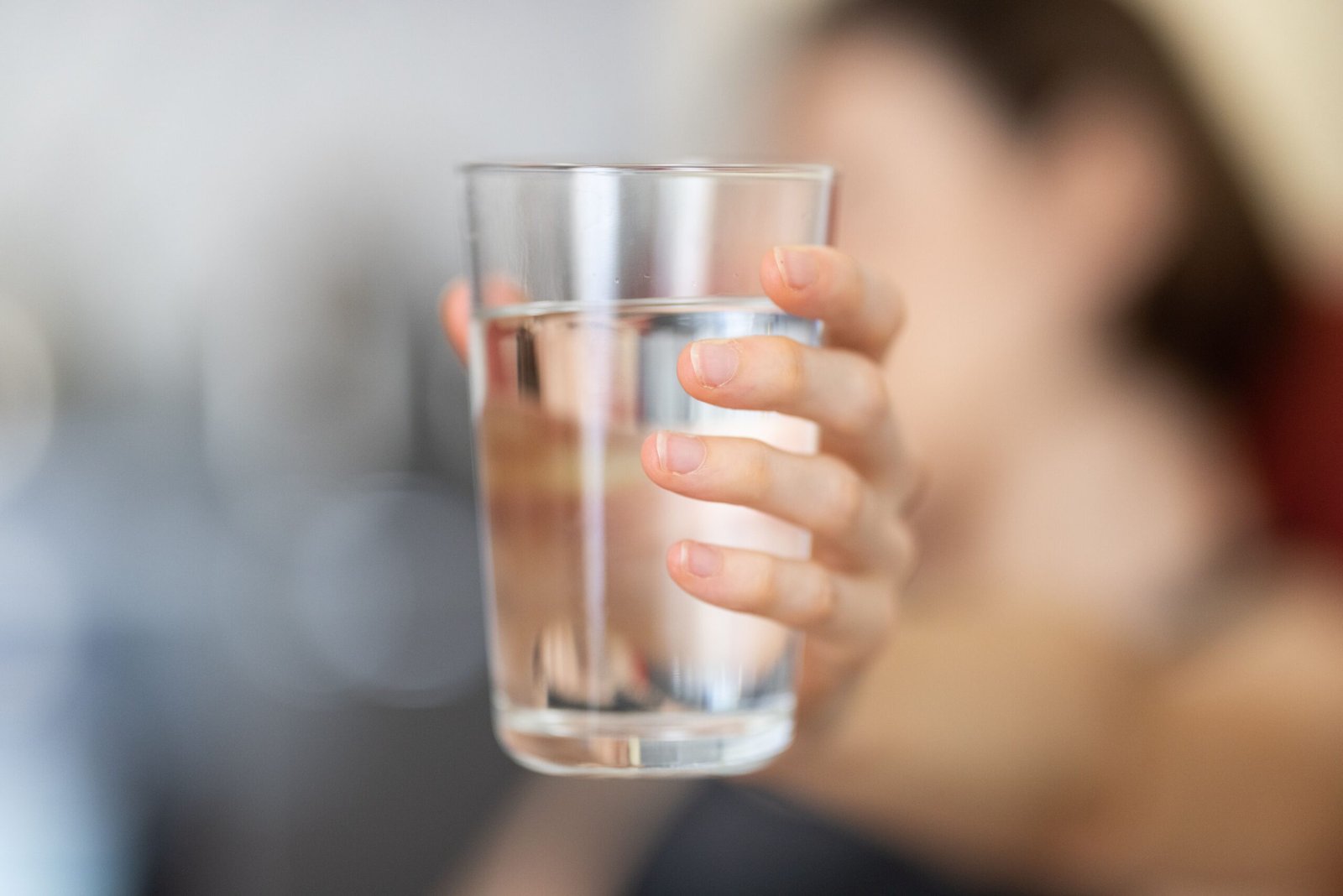 Person holding a clear glass of water, staying hydrated to avoid signs of dehydration