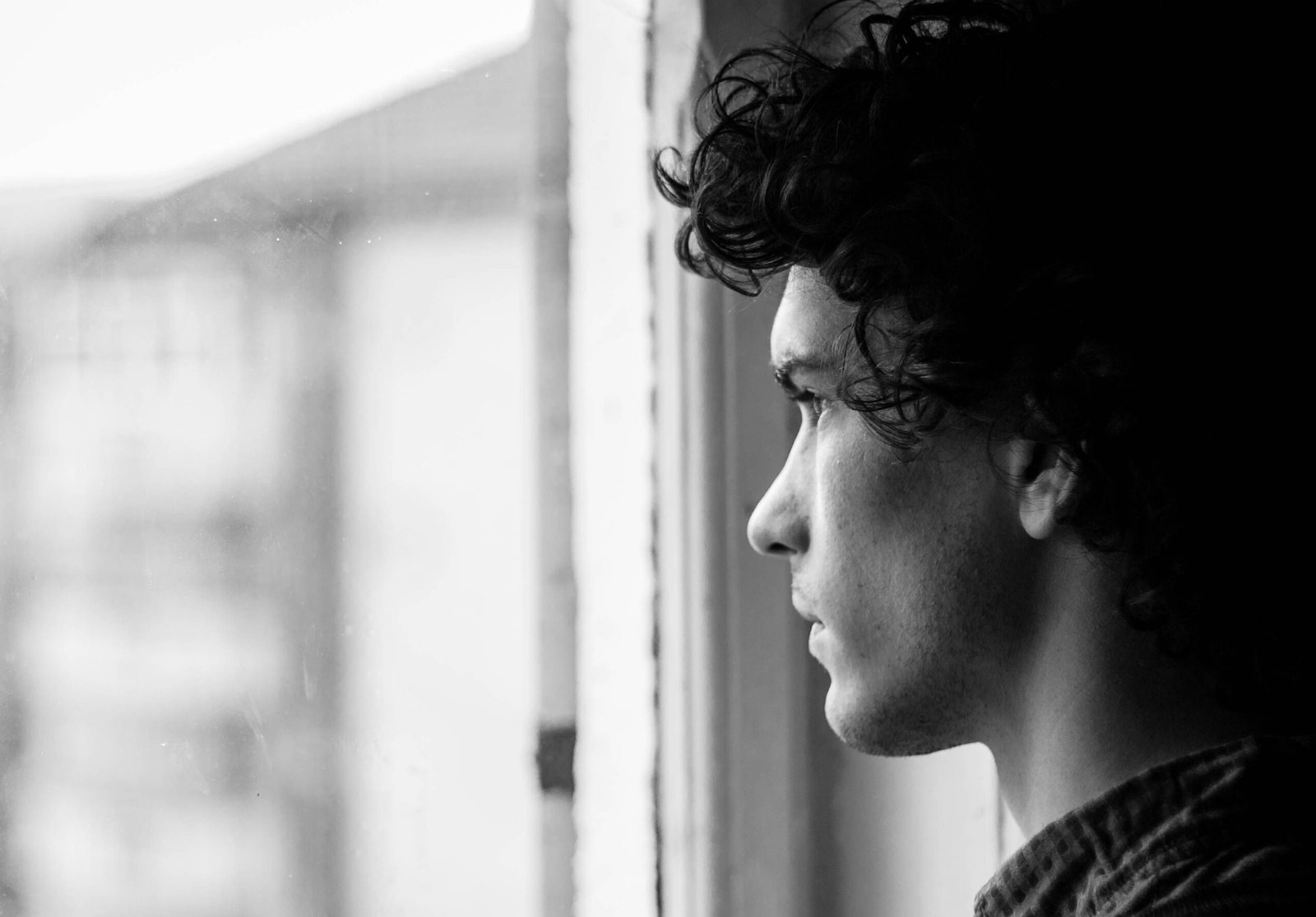 Man looking thoughtfully out of a window, reflecting on signs of depression in men