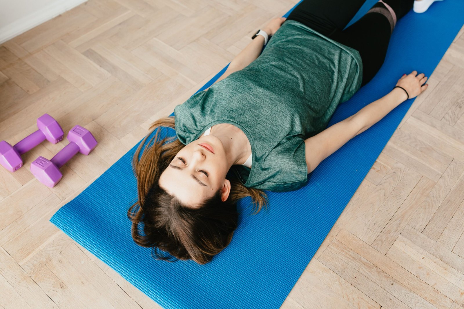 Woman lying in shavasana pose on a yoga mat, the resting position used for yoga nidra