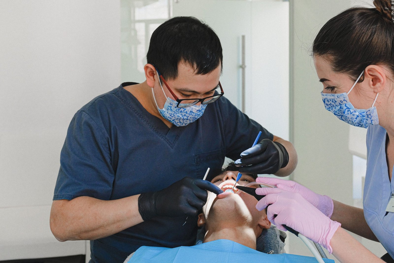 Two dental professionals conducting a teeth cleaning appointment on a patient in a modern clinic