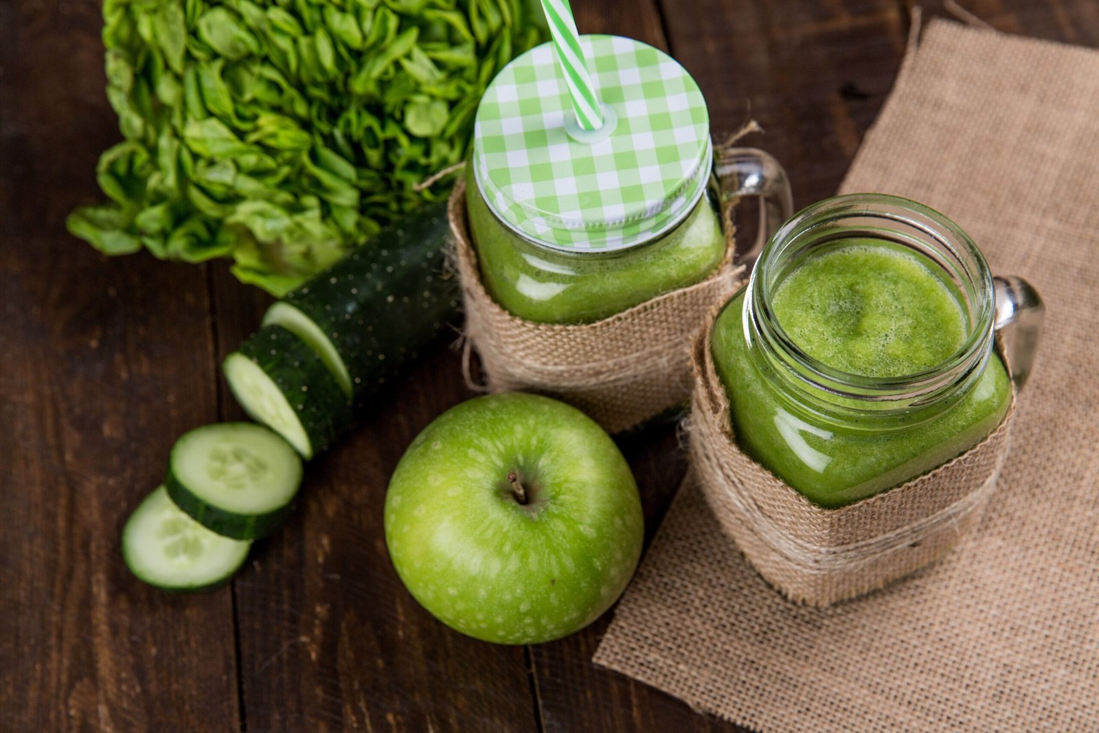 Green algae-based smoothies in glass jars alongside fresh produce, illustrating a spirulina-rich diet